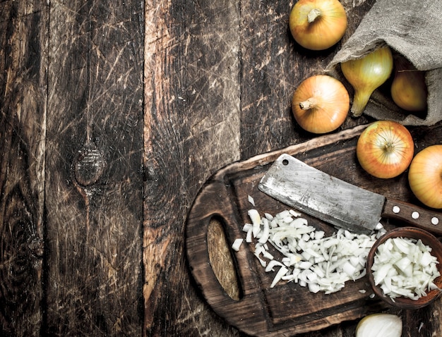 Fresh onion with old hatchet on a cutting board on a wooden background