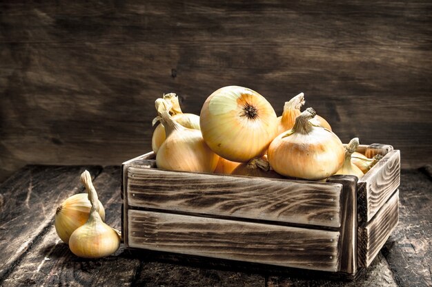 Fresh onions in an old box on a wooden background