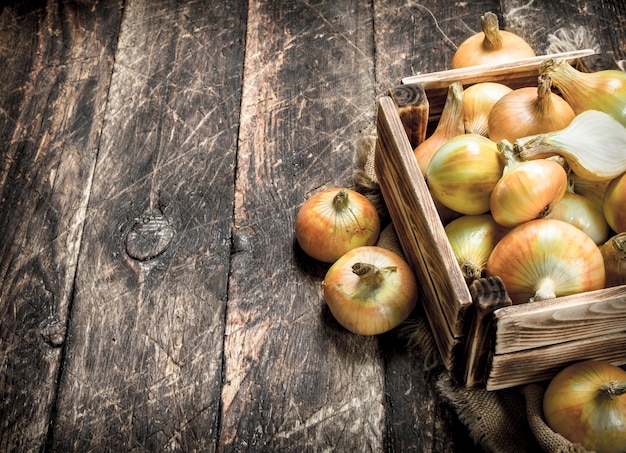 Fresh onions in an old box. On a wooden background.