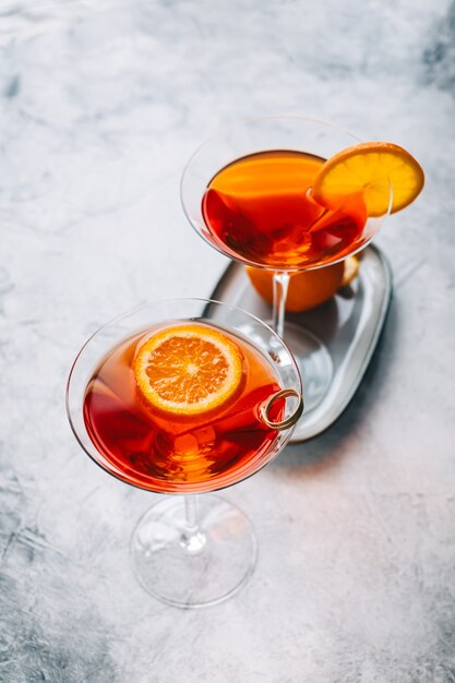 Fresh orange cocktail in martini glass with slice of orange on the table.