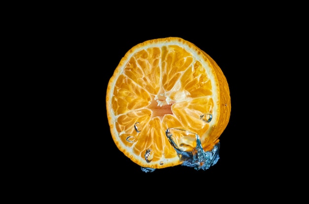 Fresh orange falling in water with splash on black background