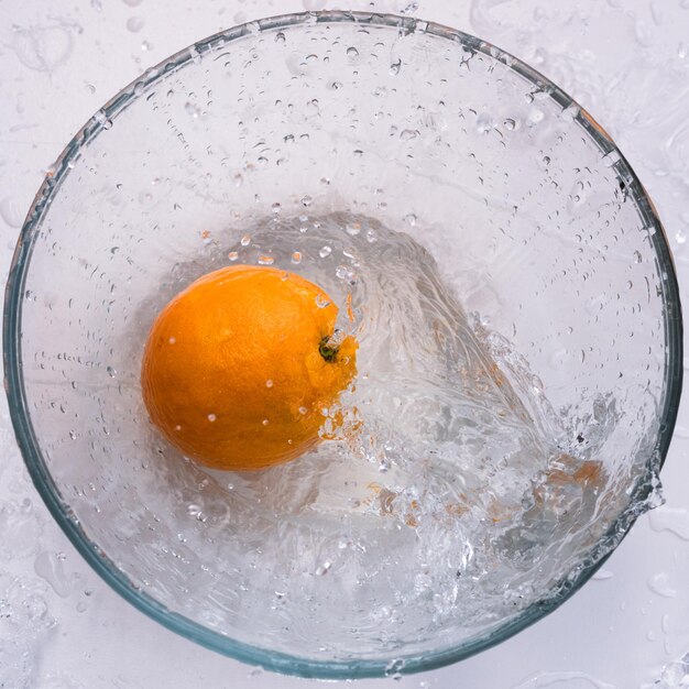 Fresh orange flies into a bowl of water