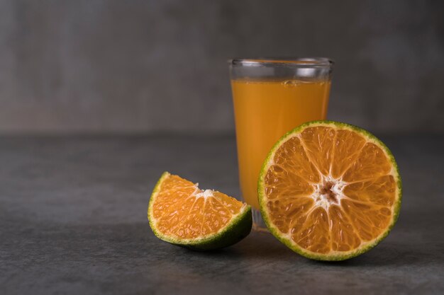 Fresh orange fruits and juice on stone table. 