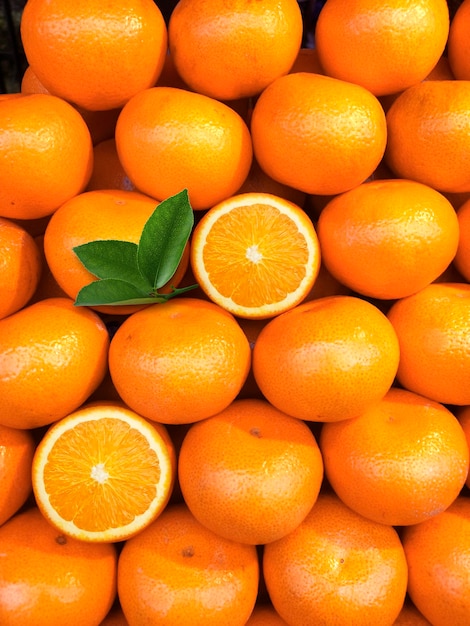 Fresh orange fruits with leaves as background top view