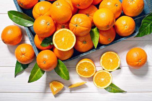 Fresh orange fruits with leaves on wooden table