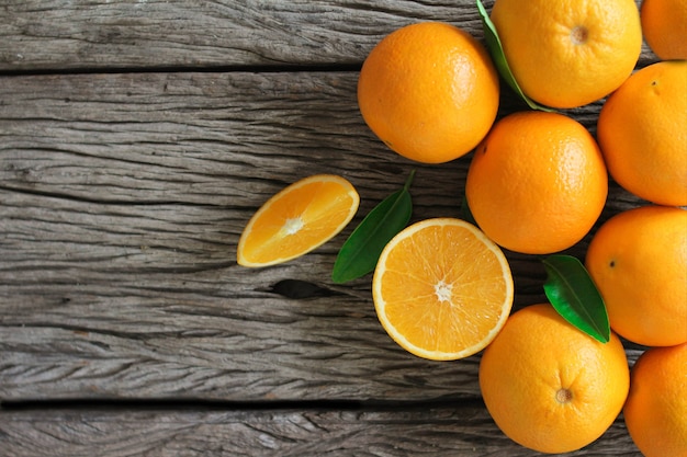 Fresh orange fruits with leaves on wooden table