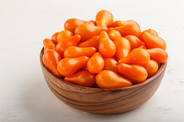 Fresh orange grape tomatoes in wooden bowl. side view.