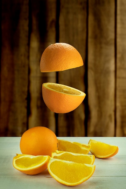 Fresh orange hovered in the air on a light wooden background Levitation of orange on wood background with space for text