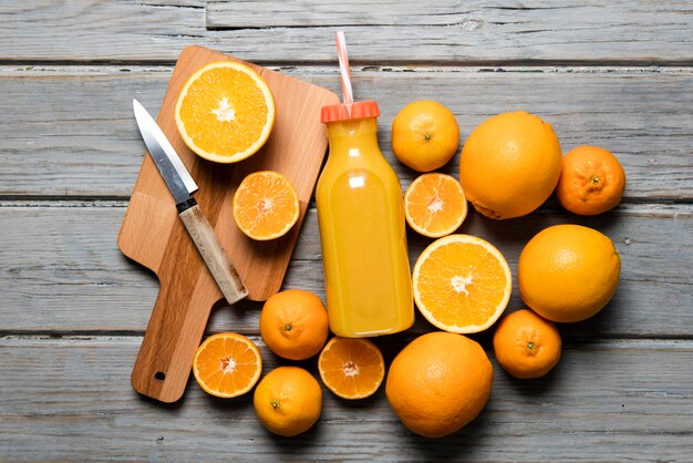 Fresh orange juice in a bottle with oranges on a rustic wooden background