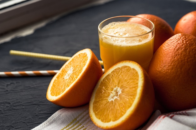 Fresh orange juice and fresh fruit oranges on a black surface