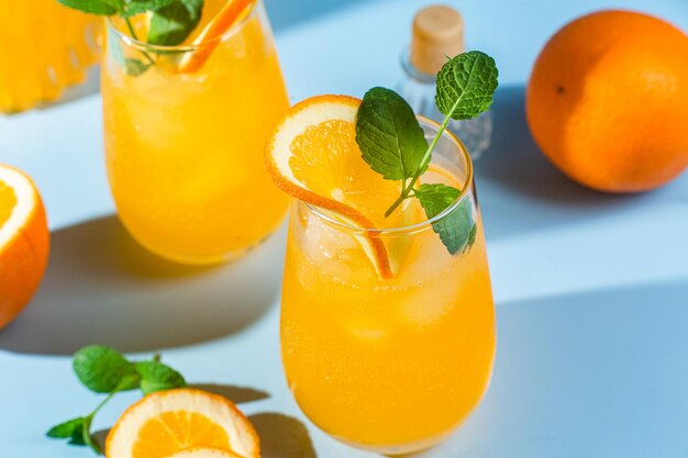 Свежевыжатый апельсиновый сок со льдом в стакане на синем фоне апельсиновый коктейль