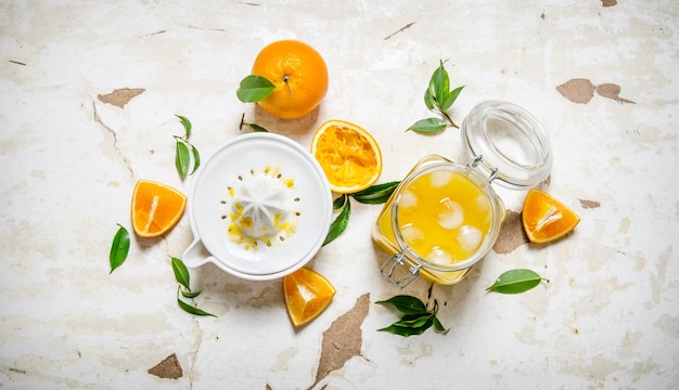 Fresh orange juice with ice, with slices of oranges and a juicer. On rustic table. Top view