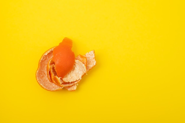 Fresh orange mandarin peel on yellow background