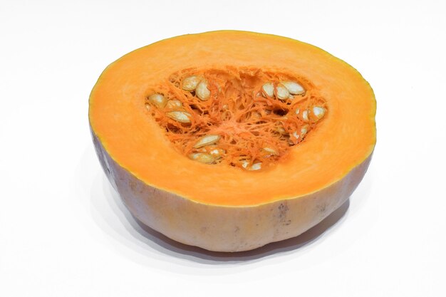 Fresh orange pumpkin cut in half with seeds, photographed against white clipping background