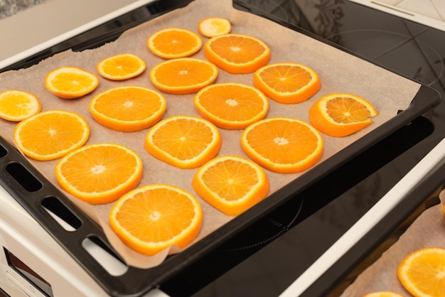 写真 手作りの冬やクリスマスの装飾のために乾燥する準備ができているオーブントレイの新鮮なオレンジスライス選択的な焦点