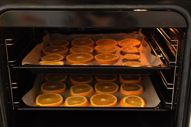 Fette d'arancia fresche sulla teglia da forno pronte per l'essiccazione per decorazioni invernali o natalizie fatte a mano messa a fuoco selettiva