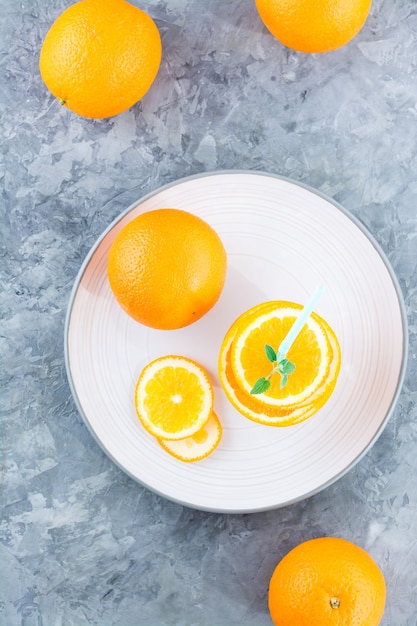 Fresh orange slices in a stack, mint leaves and a straw for a drink  