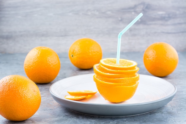 Свежие дольки апельсина в стопке и трубочка для напитка
