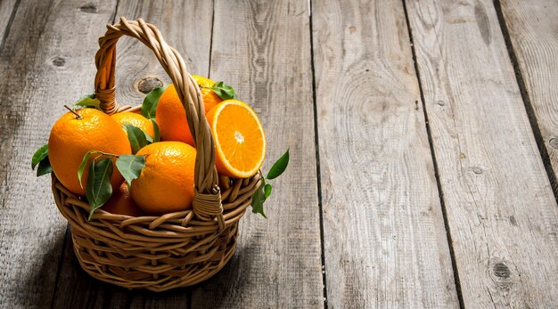 Photo fresh oranges in the basket with leaves.