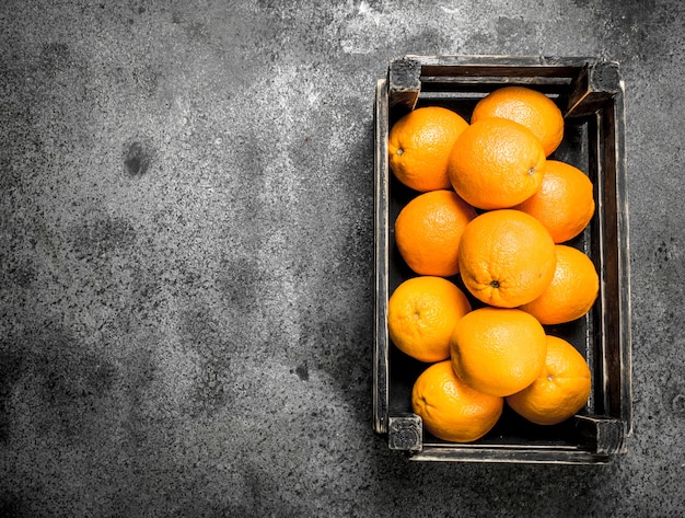 Fresh oranges in a box on a rustic background