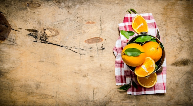 Fresh oranges in the bucket on the fabric.