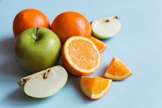 Fresh oranges and green apples on the blue surface