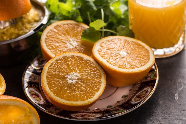 Fresh oranges juicer juice tropical fruits and herbs on concrete board.