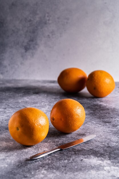 Fresh oranges and knife on concrete table