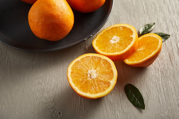 Fresh oranges in plate on wooden table