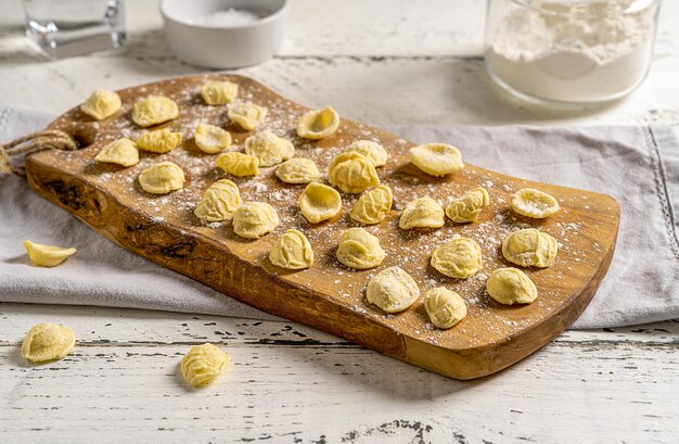 Fresh Orecchiette are typical Italian pasta of Puglia Pasta on wooden cutting board with ingredients