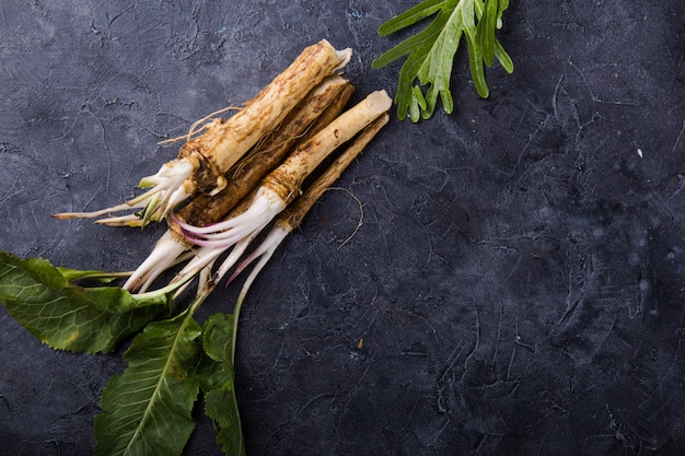 Fresh orgaanic horseradish or Horse radish root on wooden cutting board.