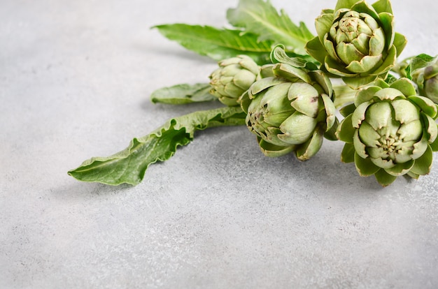 Fresh organic artichokes on a gray concrete background.