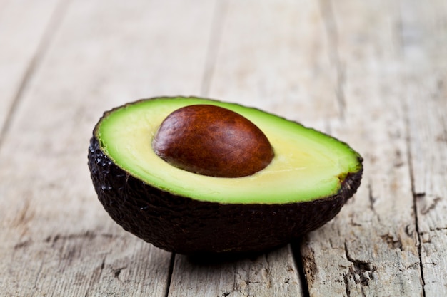 Avocado organico fresco mezzo sulla vecchia tavola di legno