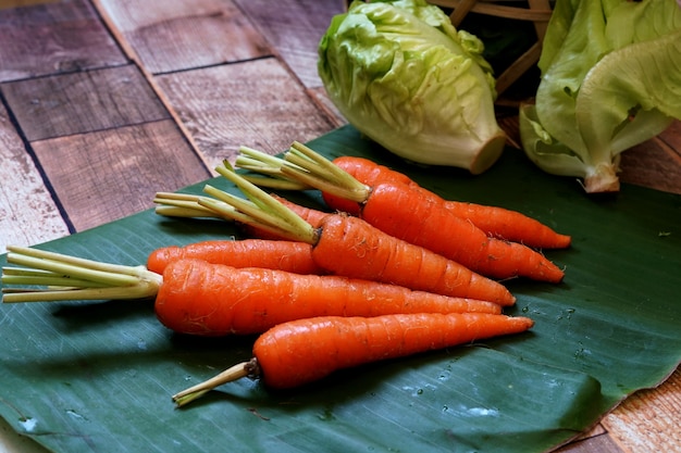 Fresh organic baby carrot and green baby cos lettuce on wooden table