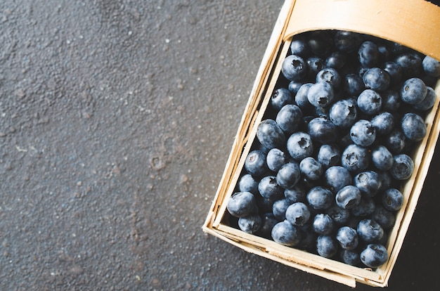 Fresh organic blueberries in basket on dark concrete