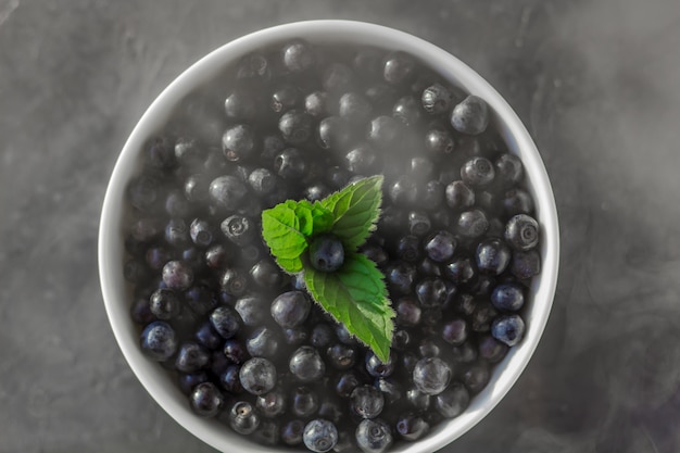 Fresh organic blueberries in a bowl on dark  in smoky effect close up. 