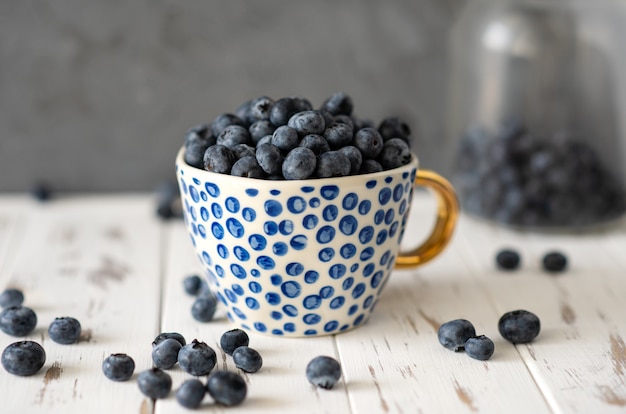 Fresh organic blueberry in cup on grey surface, copy space