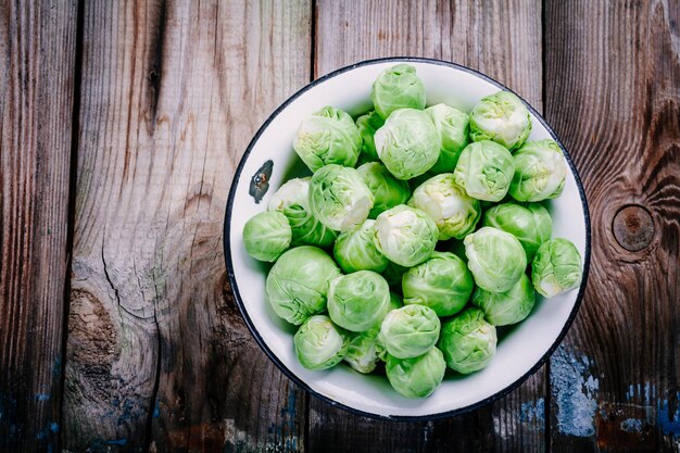 Fresh organic Brussels sprouts in a bowl on a wooden table