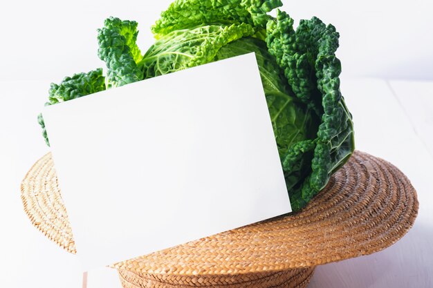 Photo fresh organic cabbage on a straw hat with blank note