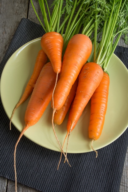 Fresh organic carrot in green dish on the rustic table.