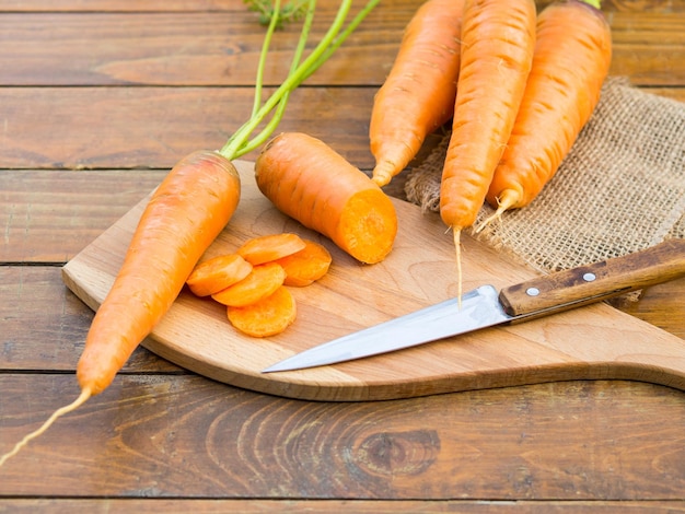 Fresh organic carrots with green leaves on wooden background Vegetables