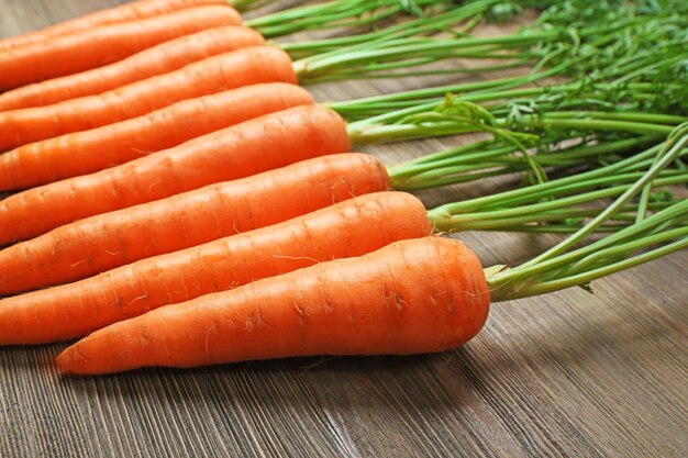 Fresh organic carrots on wooden table closeup