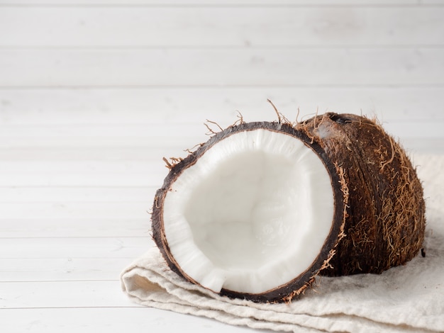 Fresh organic coconut broken into two parts on rustic wooden background,