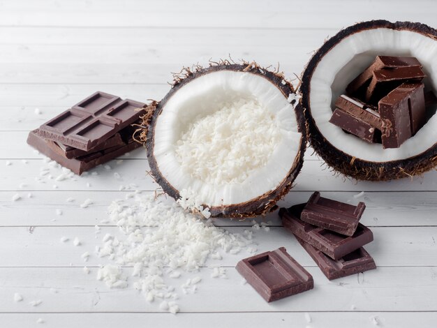 Fresh organic coconut broken into two parts with coconut on a rustic wooden background