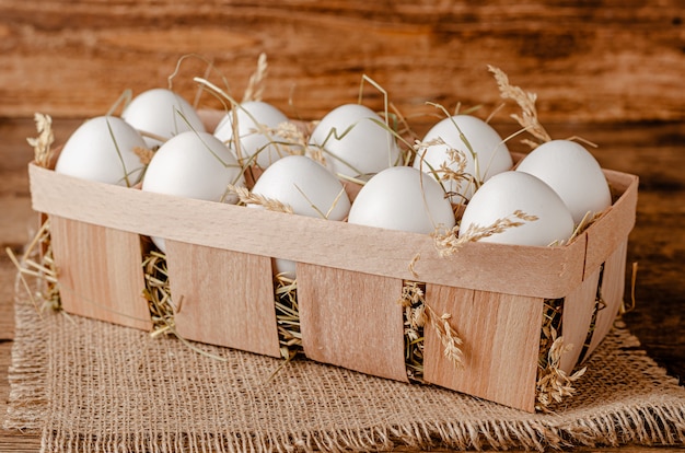 Fresh organic eggs in container on wooden space. Copy space