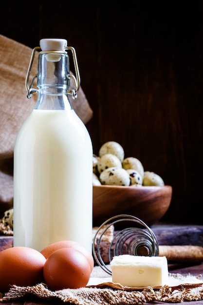 Fresh organic eggs milk and butter still life in rustic style vintage wooden background selective focus