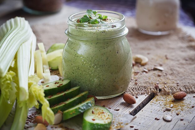 Fresh organic green smoothie with cucumber, parsley and celery on rustic wooden background