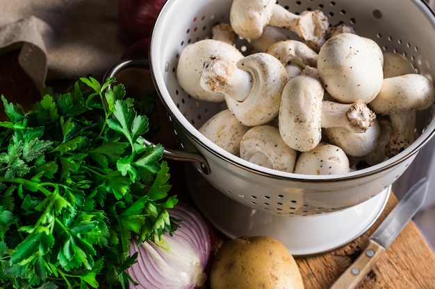 Fresh organic ingredients for preparing healthy vegetarian meal potatoes, mushrooms onion, parsley