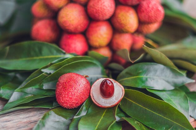 Fresh organic lychee fruit and lychee leaves on a rustic wooden surface