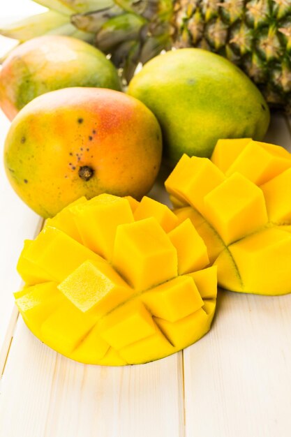 Fresh organic mango and pineapple on a white wood board